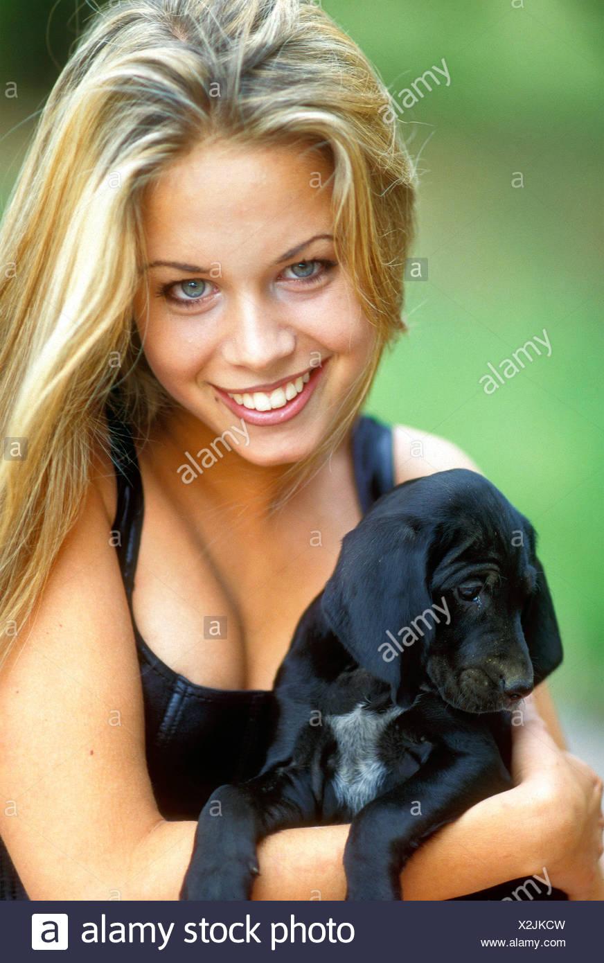Female With Long Blonde Hair Cuddling A Small Black Puppy Dog
