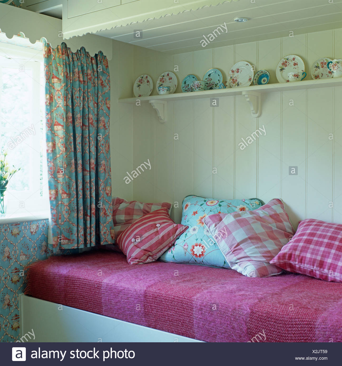 China On Shelf Above Seat With Checked And Floral Cushions And