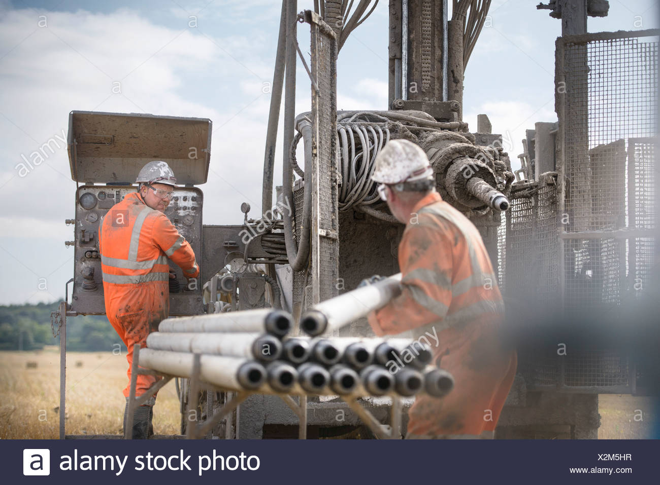 Workers in hard hats operating drilling rig Stock Photo