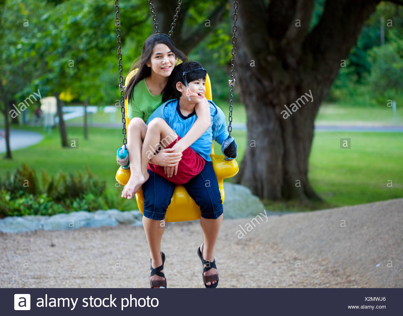 Big Sister Holding Disabled Brother On Special Needs Swing