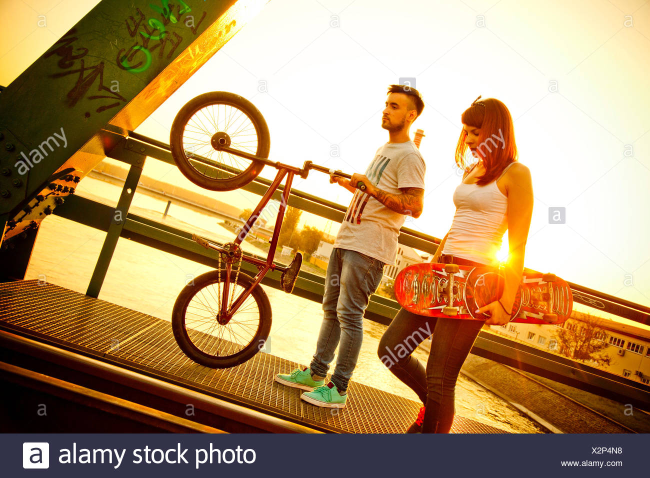 Young couple with skateboard and BMX bicycle outdoors Stock Photo