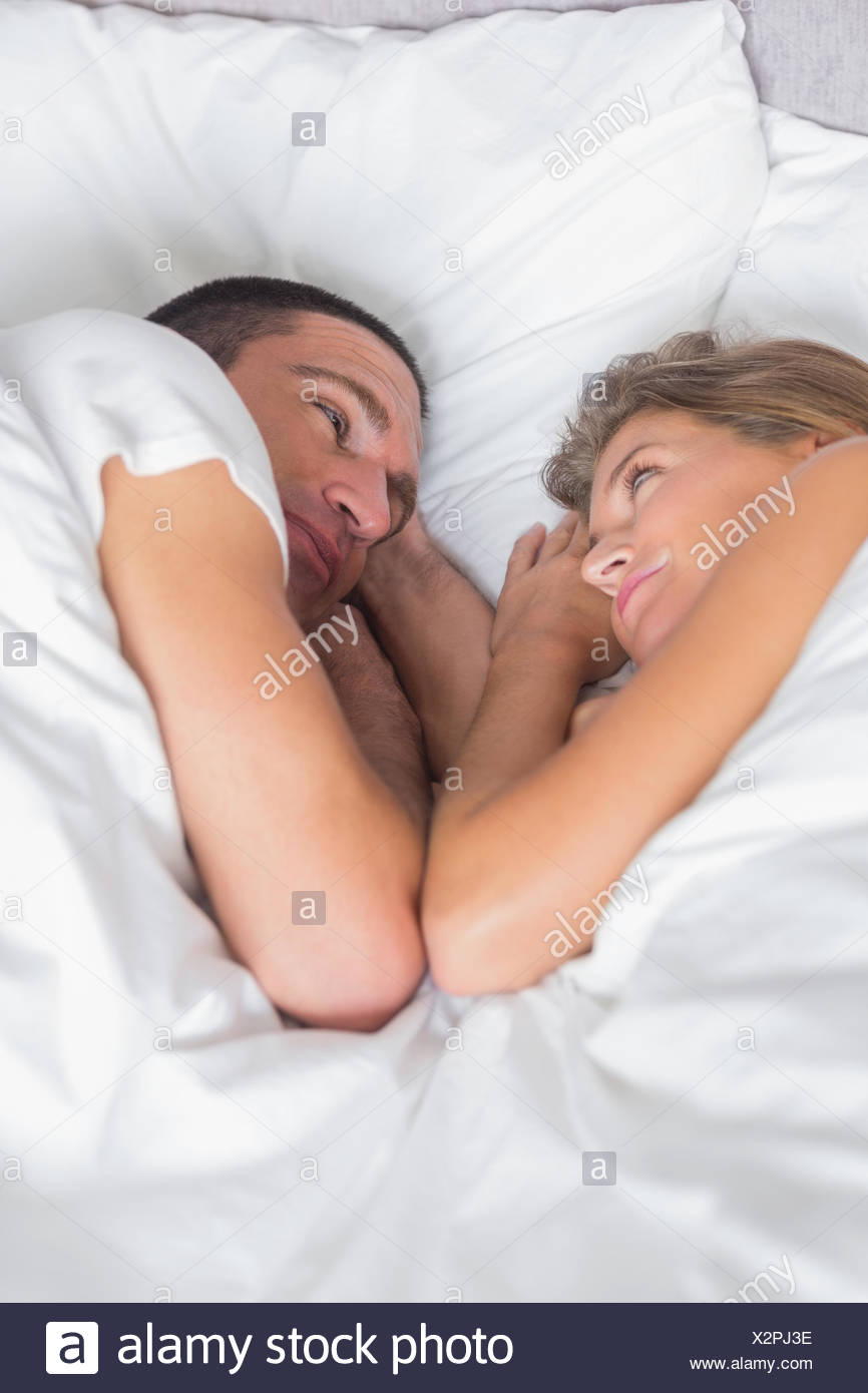 Cute Couple Lying Together In Bed At Home In Bedroom Stock