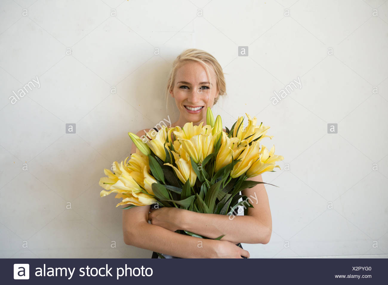 portrait of young woman holding bouquet of yellow flowers X2PYG0