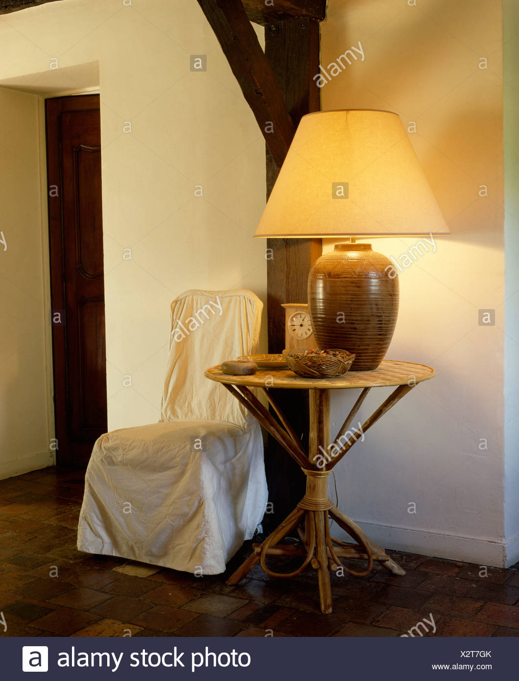 Lighted Lamp On Rustic Wooden Table Beside Chair With Cream