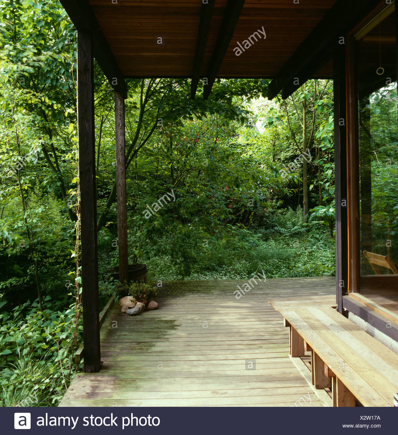 Wooden Benches And Decking On Veranda Of House Set In Woodland
