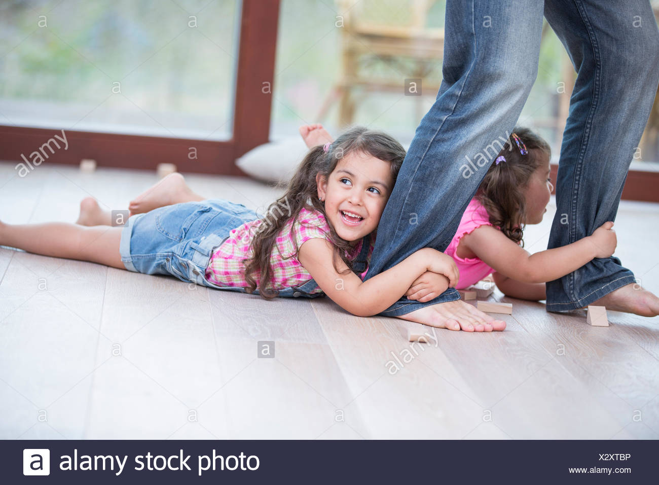 Low Section Of Father Dragging Girls On Hardwood Floor Stock Photo