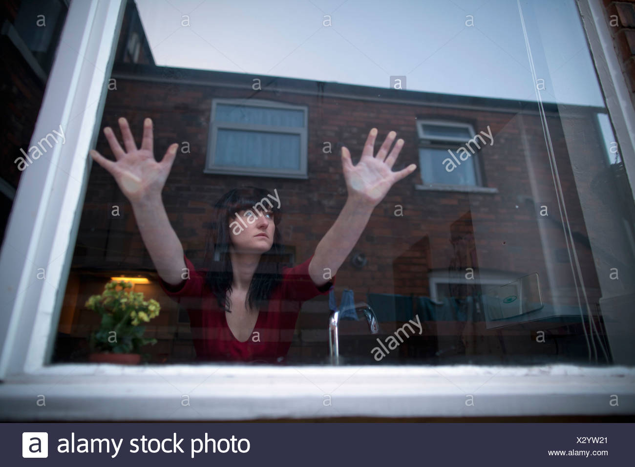 Woman in kitchen leaning on window Stock Photo