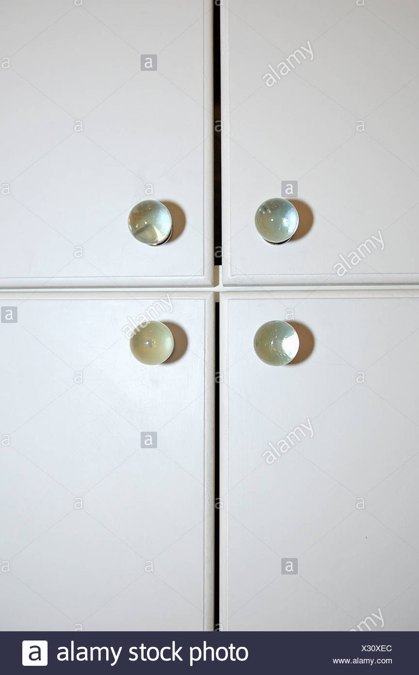 Close Up Of Clear Glass Knobs On White Cupboard Doors Stock Photo