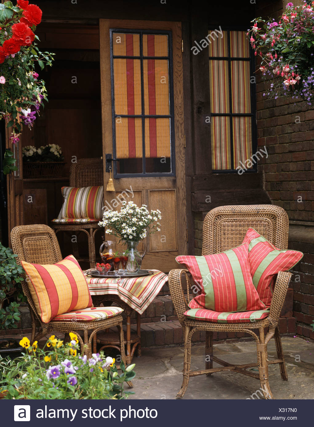 Striped Cushions On Wicker Chairs On Patio In Front Of French Windows With Striped Blinds Stock Photo Alamy