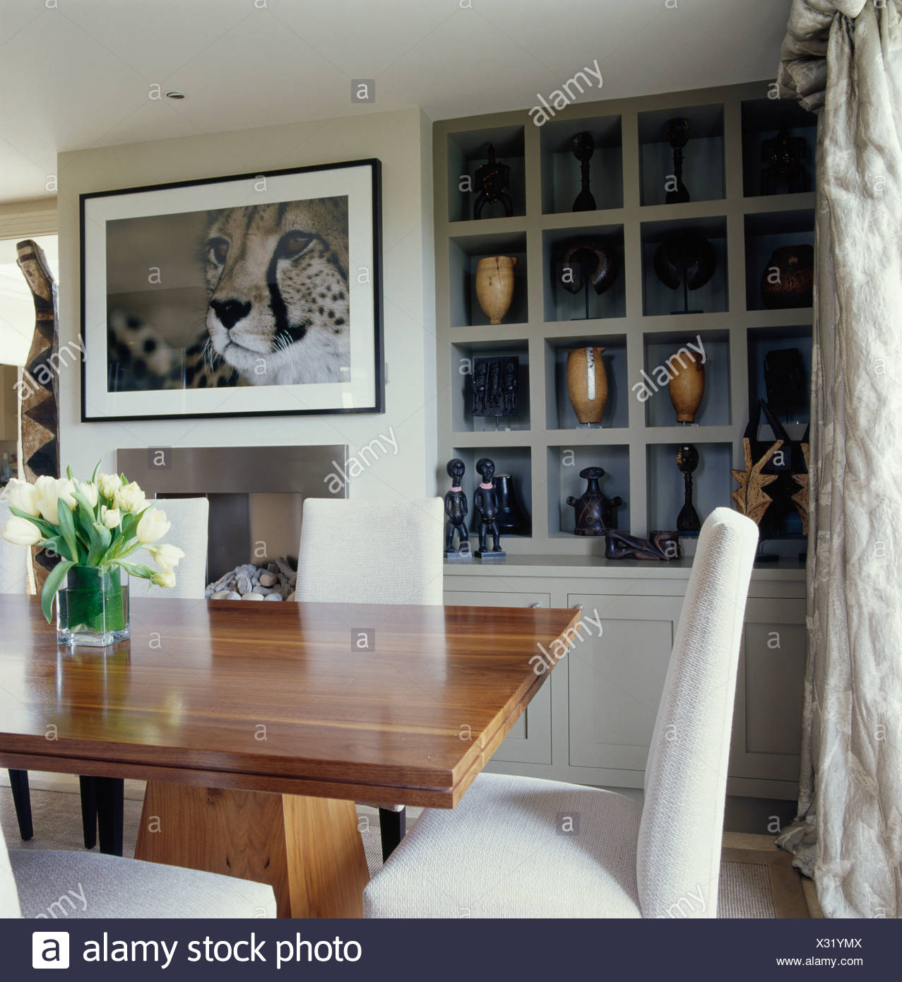 Large Picture Above Fireplace In Cream Dining Room With Cube Alcove Shelving And Cream Chairs At Plain Wood Table Stock Photo Alamy