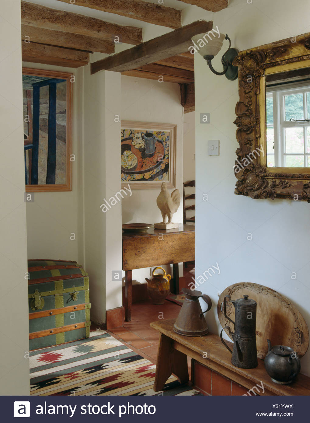 Ornate Mirror Above Wooden Bench With Old Pewter Jugs In Small Cottage Hall With Ikat Rug Stock Photo Alamy