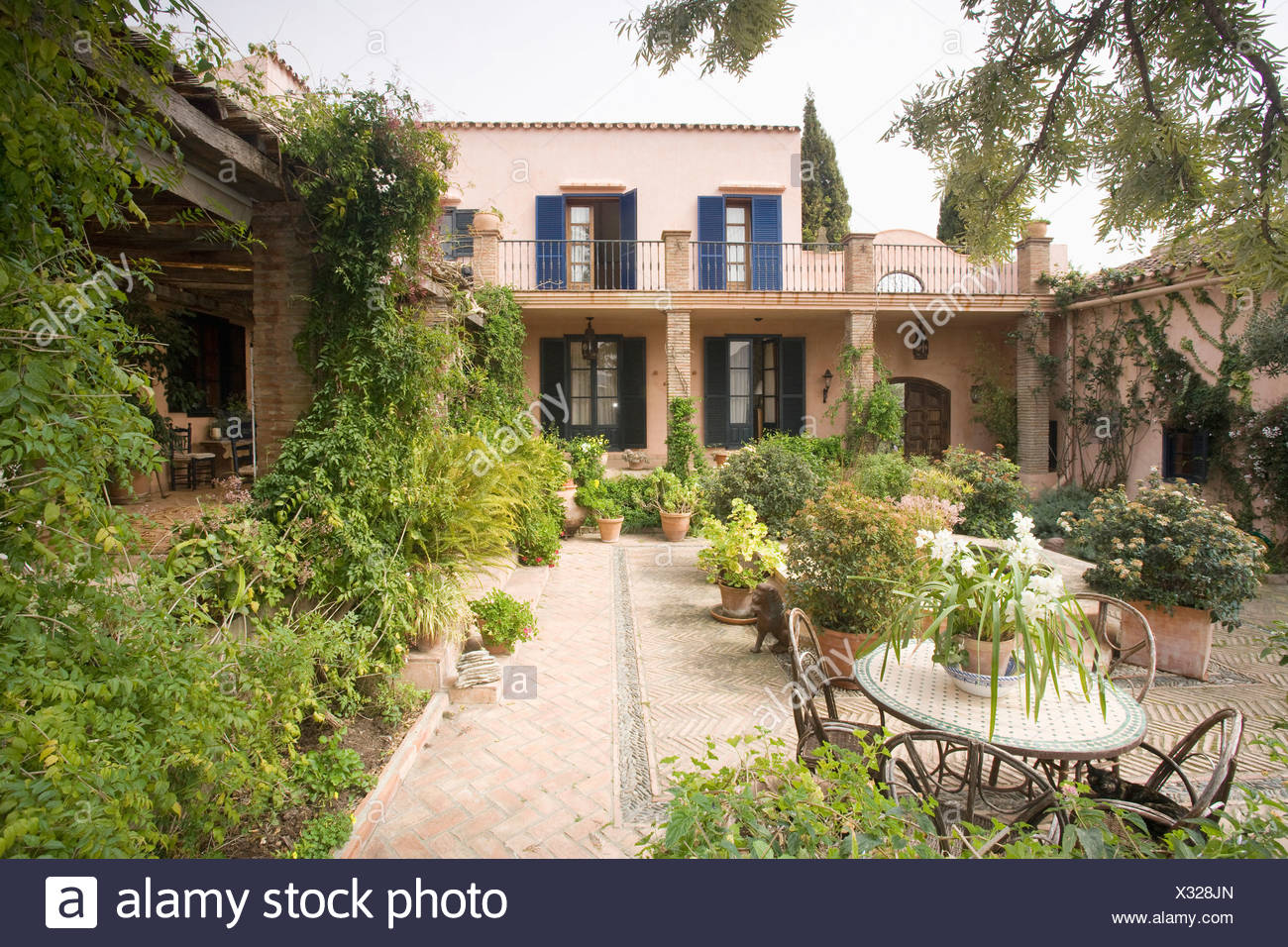 Table And Chairs On Patio In Spanish Courtyard Garden With