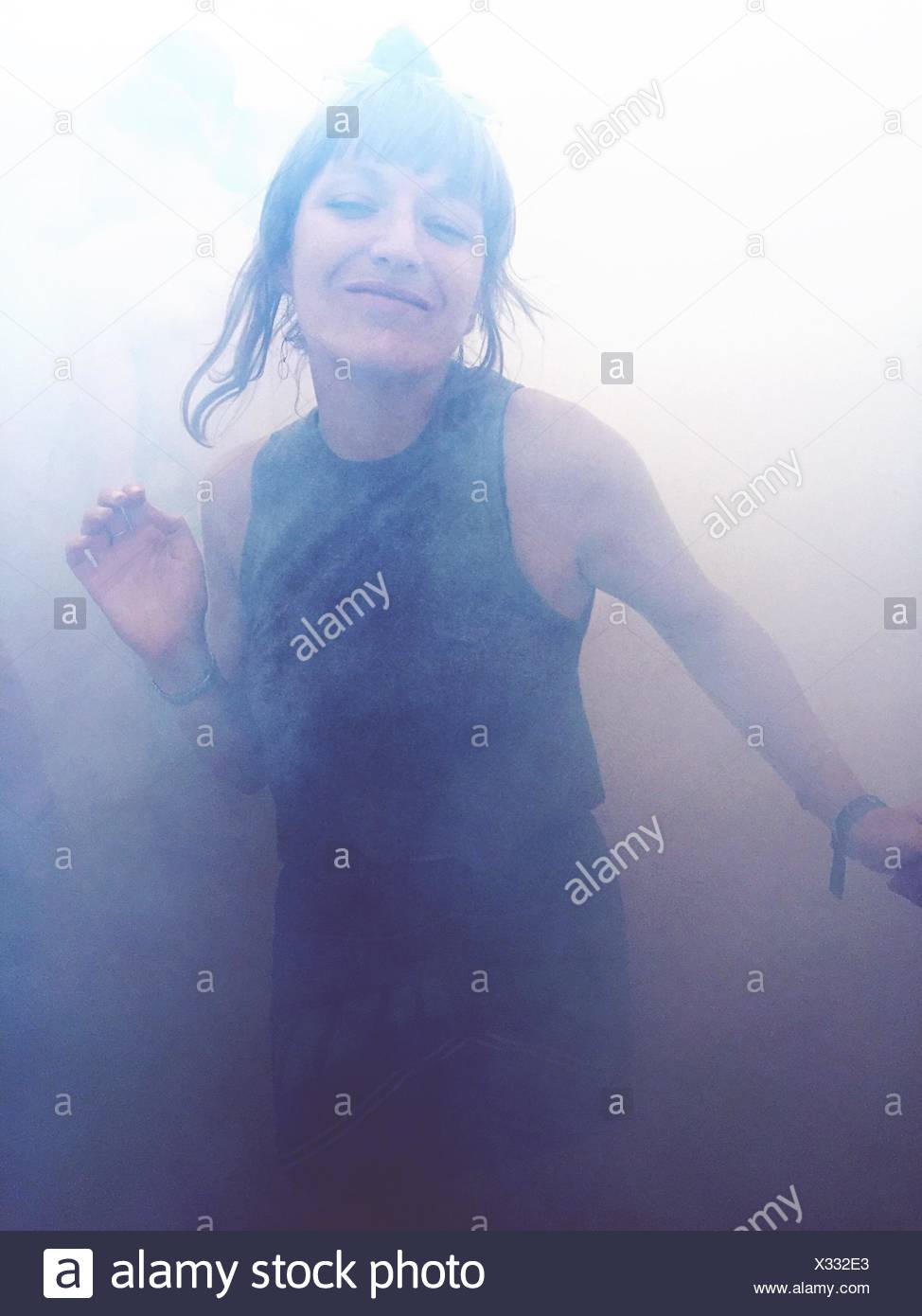 Portrait Of Happy Woman Dancing In Smoke Stock Photo