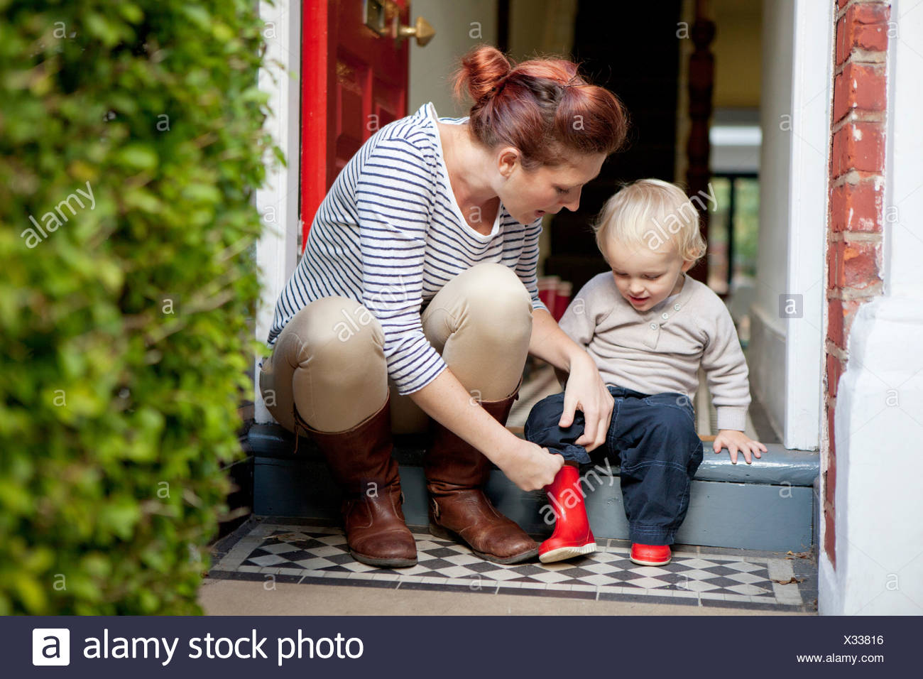 Boy Putting On Rubber Boots High Resolution Stock Photography and