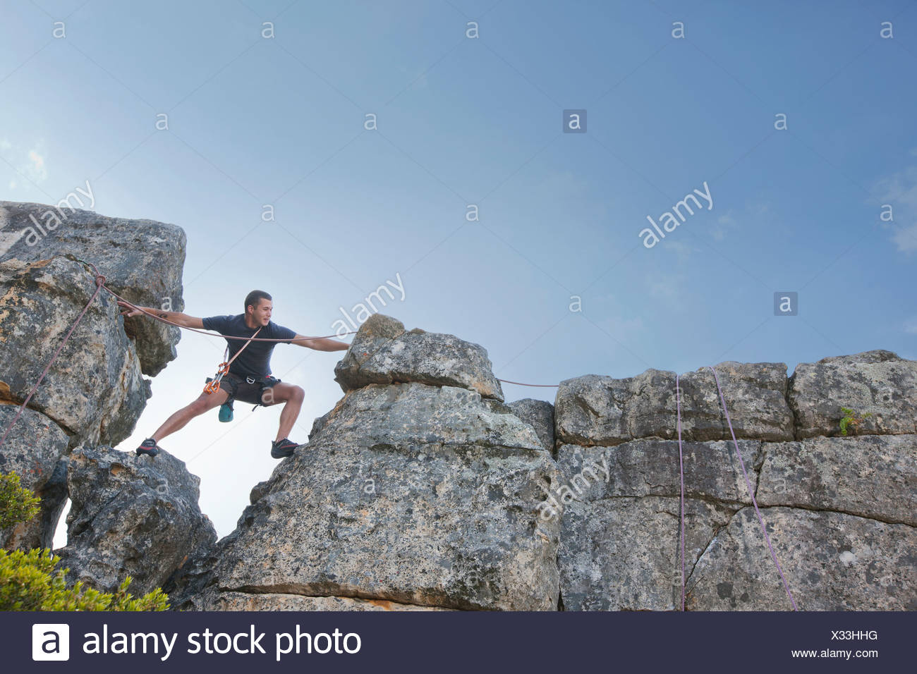 Young man stepping and reaching on rock climb Stock Photo