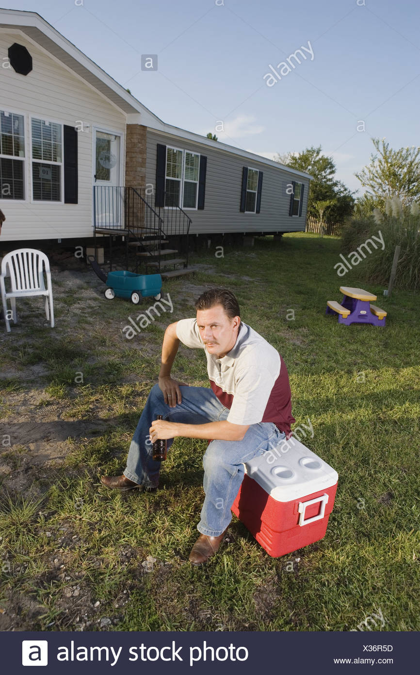 Man Sitting On An Ice Chest Holding A Drink Bottle In Front Of