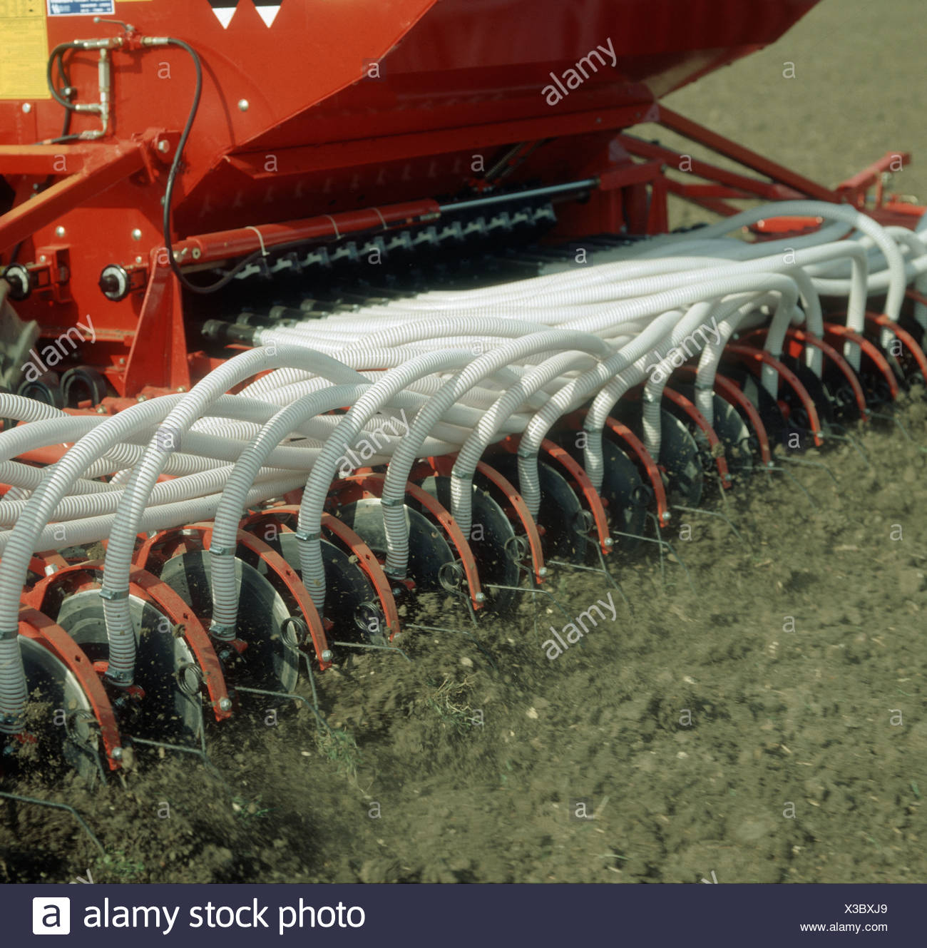 Rear end of a Massey Ferguson pneumatic seed drill planting a cereal crop - Stock Image