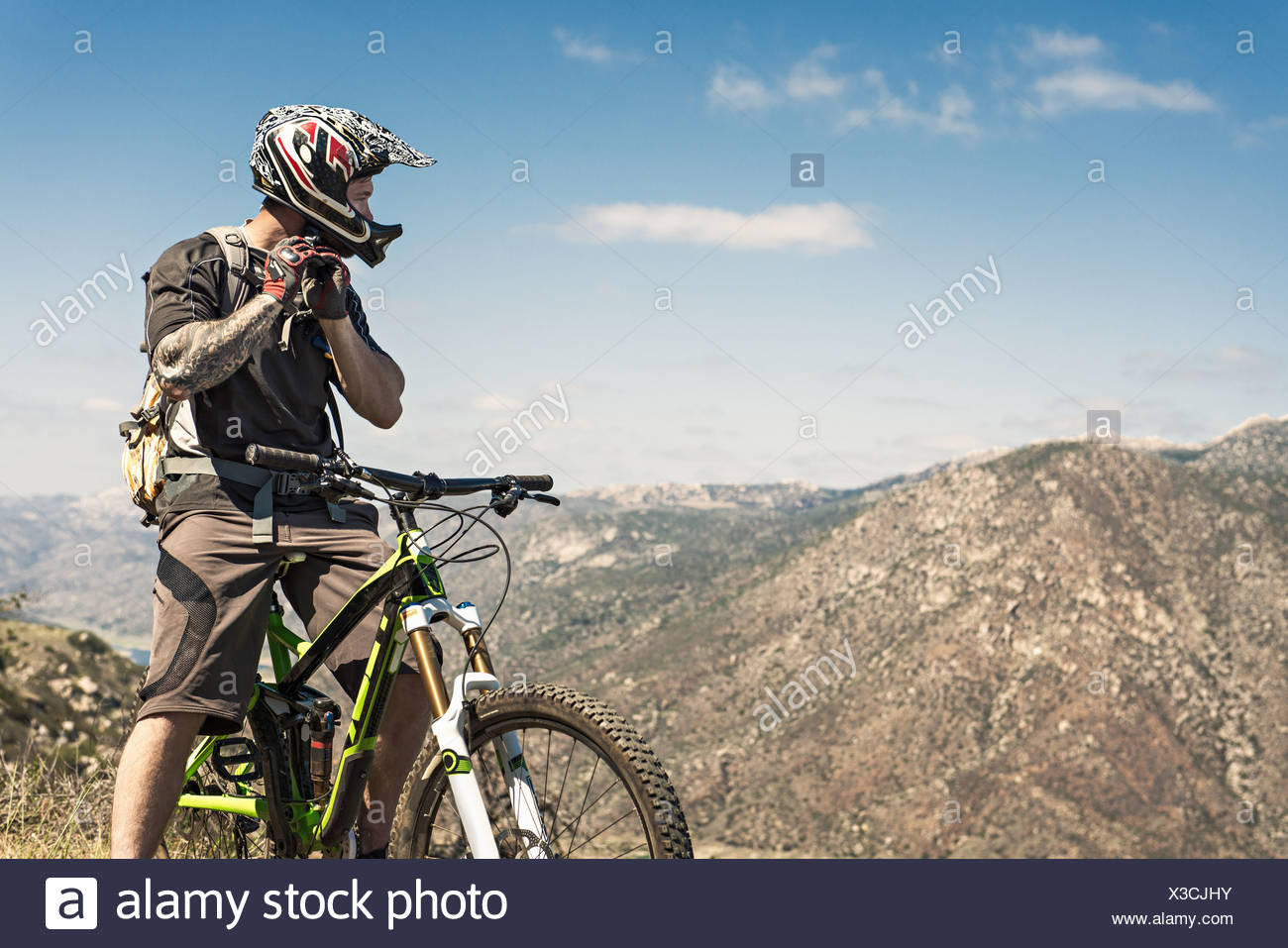 Downhill mountain biker putting on helmet Stock Photo