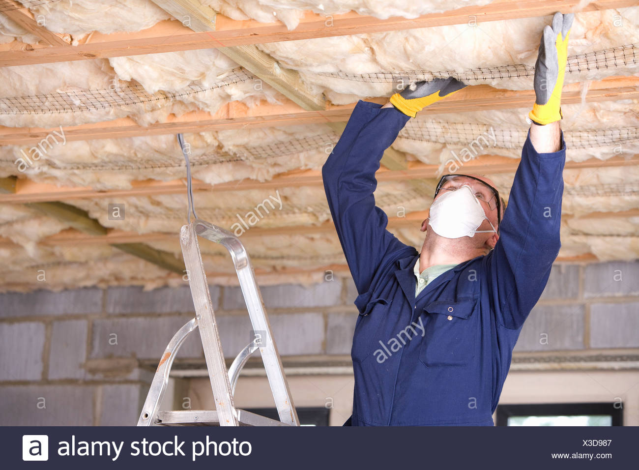 Man Wearing Protective Mask And Installing Ceiling Insulation
