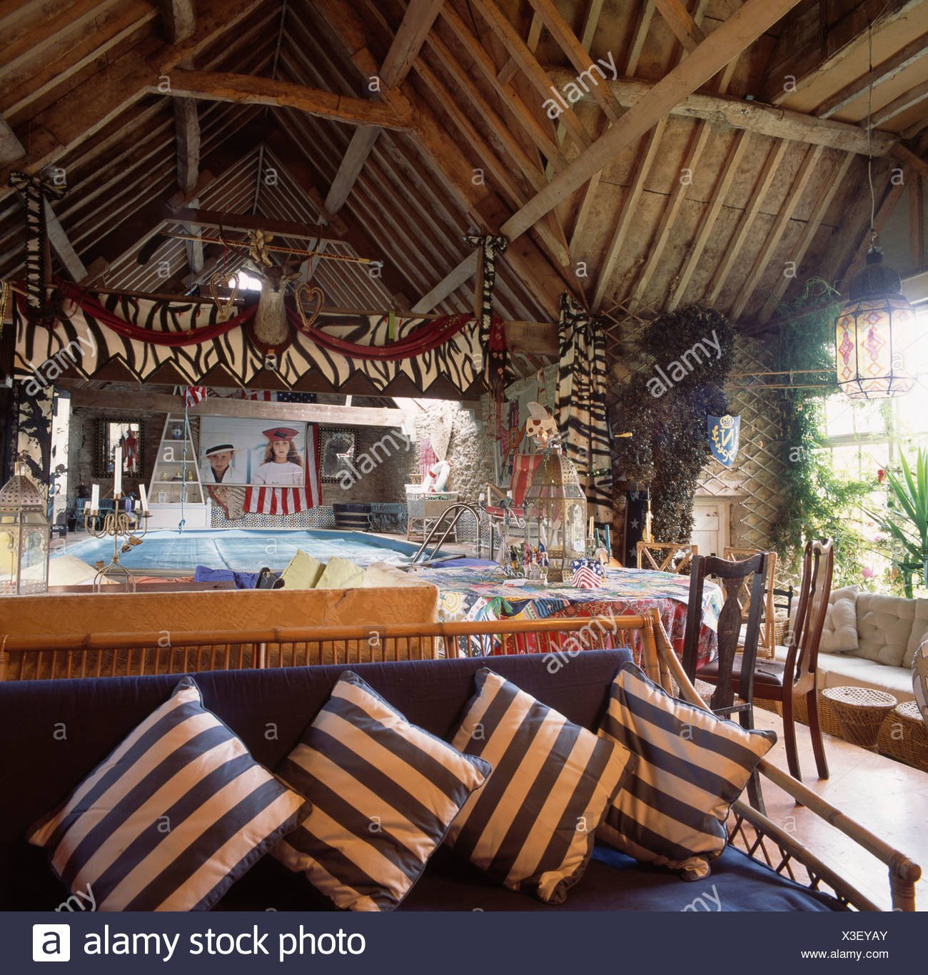 Blue And White Striped Cushions On Cane Sofa In Barn Conversion