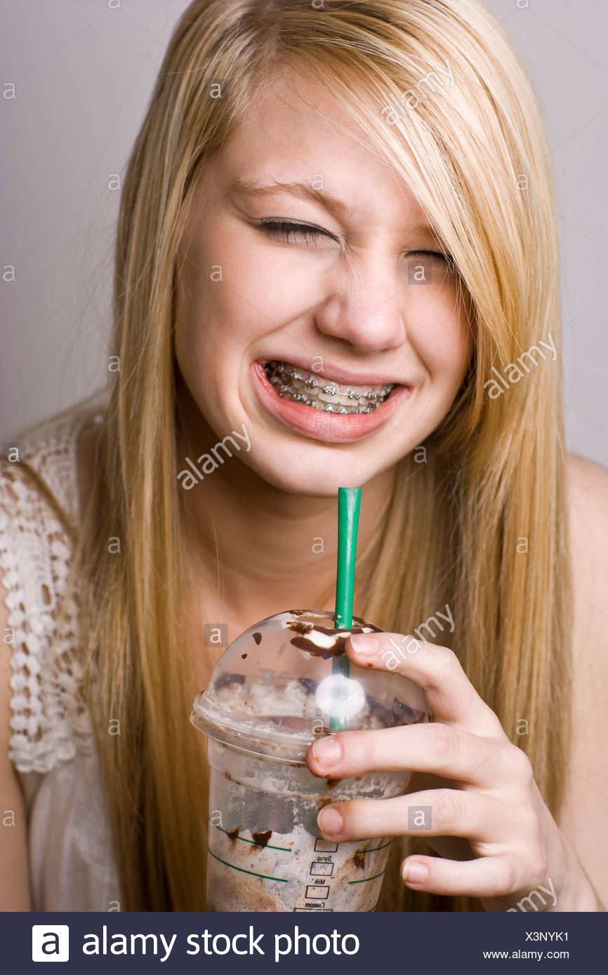 Teenage Girl Wincing From A Brain Freeze While Drinking Iced Coffee Teenage Girl Wincing From A Brain Freeze While Drinking Iced Coffee