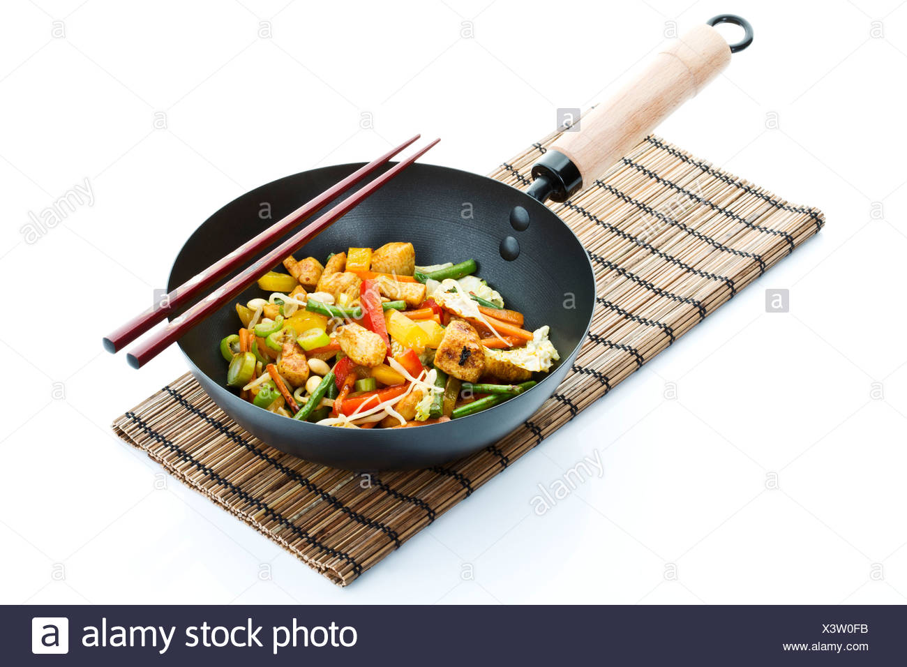Chinese food in wok with chopsticks placed on straw mat Stock Photo - Alamy