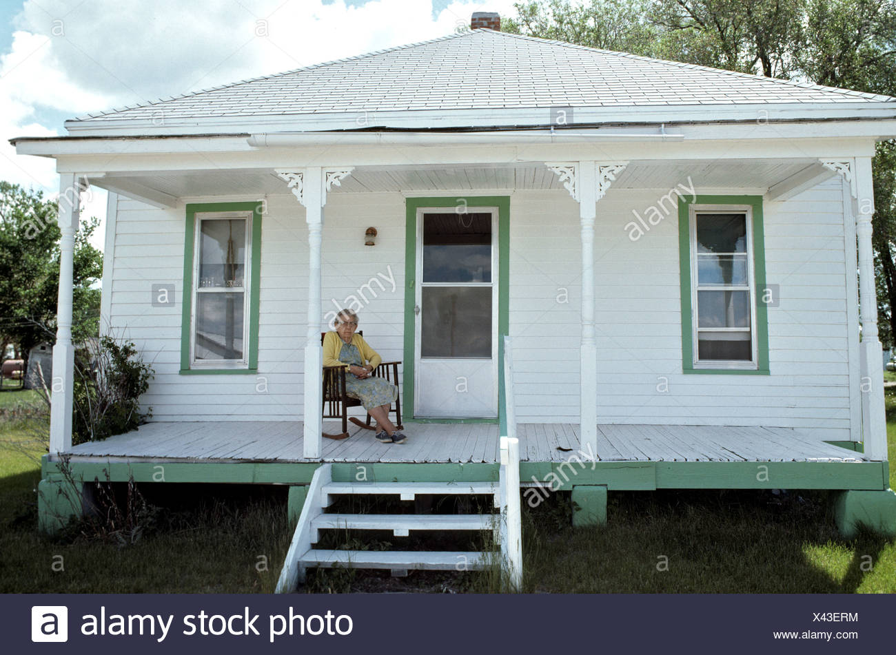 Old Woman On Her Porch Of Her Wooden Raised Floor House Stock