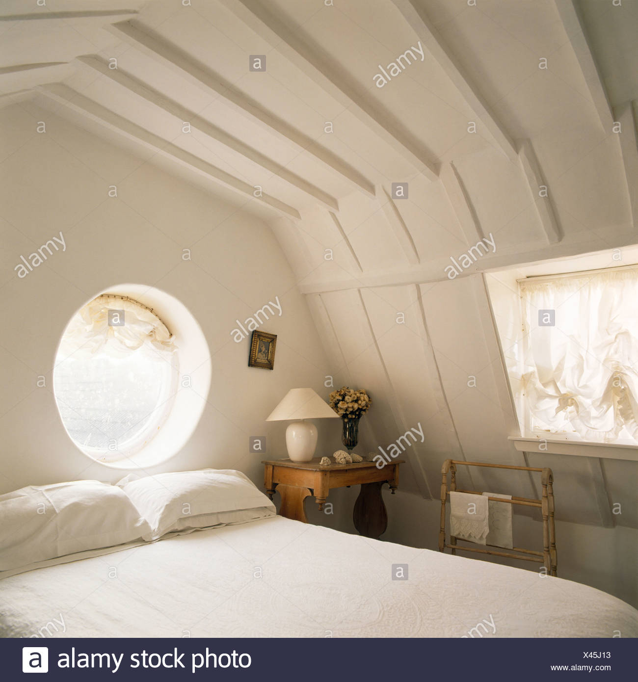Circular Window Above Bed With White Bedlinen In Cream Attic