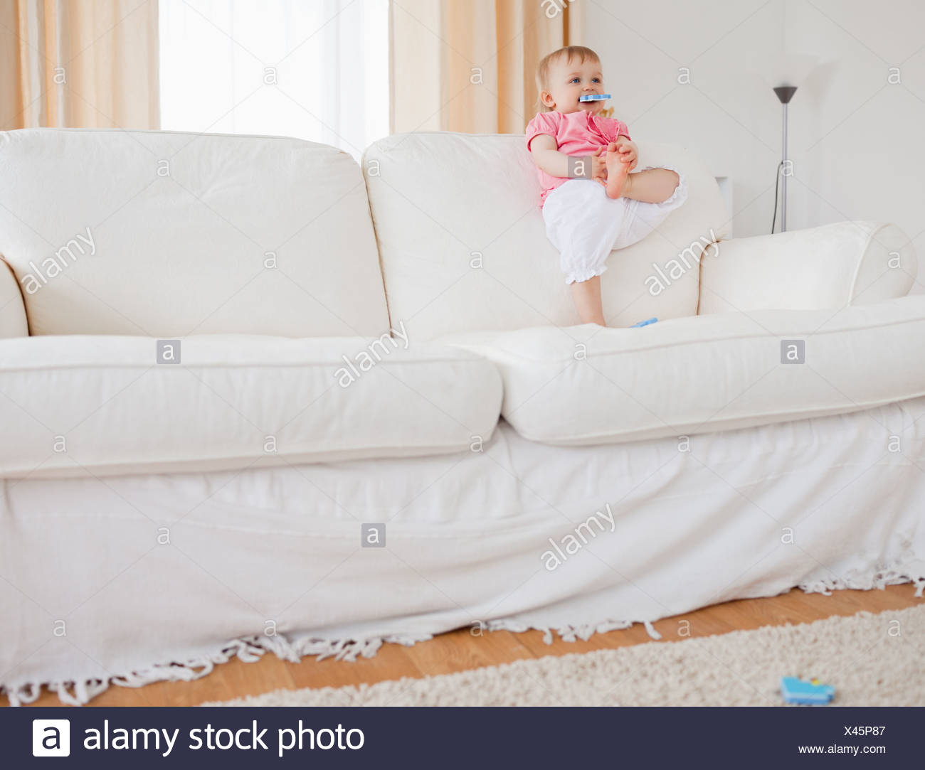 Lovely Blond Baby Playing With Puzzle Pieces While Standing On A