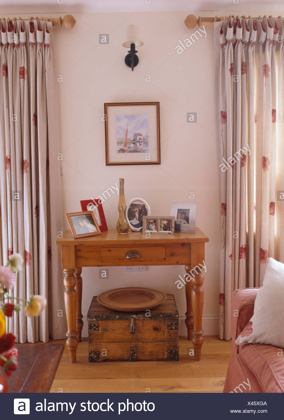 Old Wooden Box Below Small Pine Table Between Windows With Red