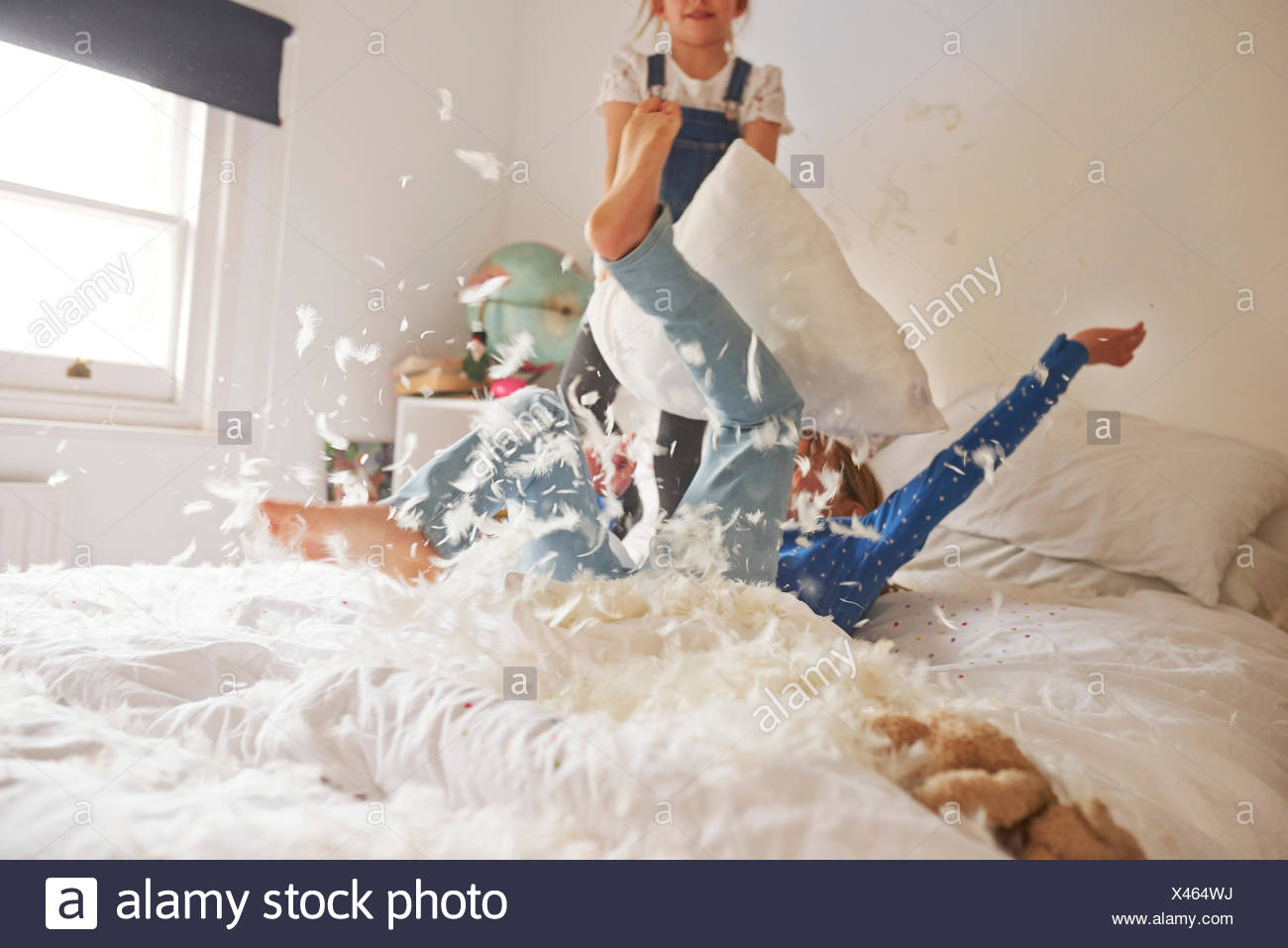 Two Sister Having Feather Pillow Fight On Bed Stock Photo