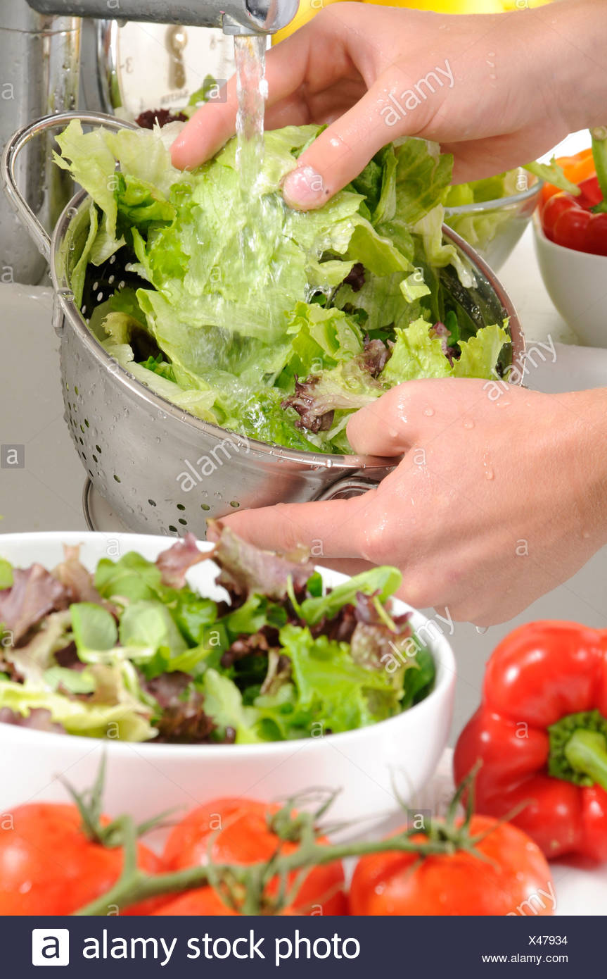 Man Washing Salad Greens In Collander At Kitchen Sink Stock Photo