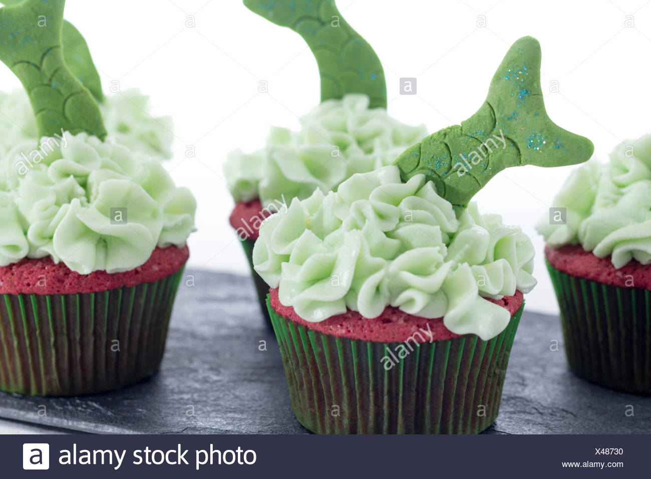 Tasty Cupcakes With Green Icing And Fish Tails Decoration On A