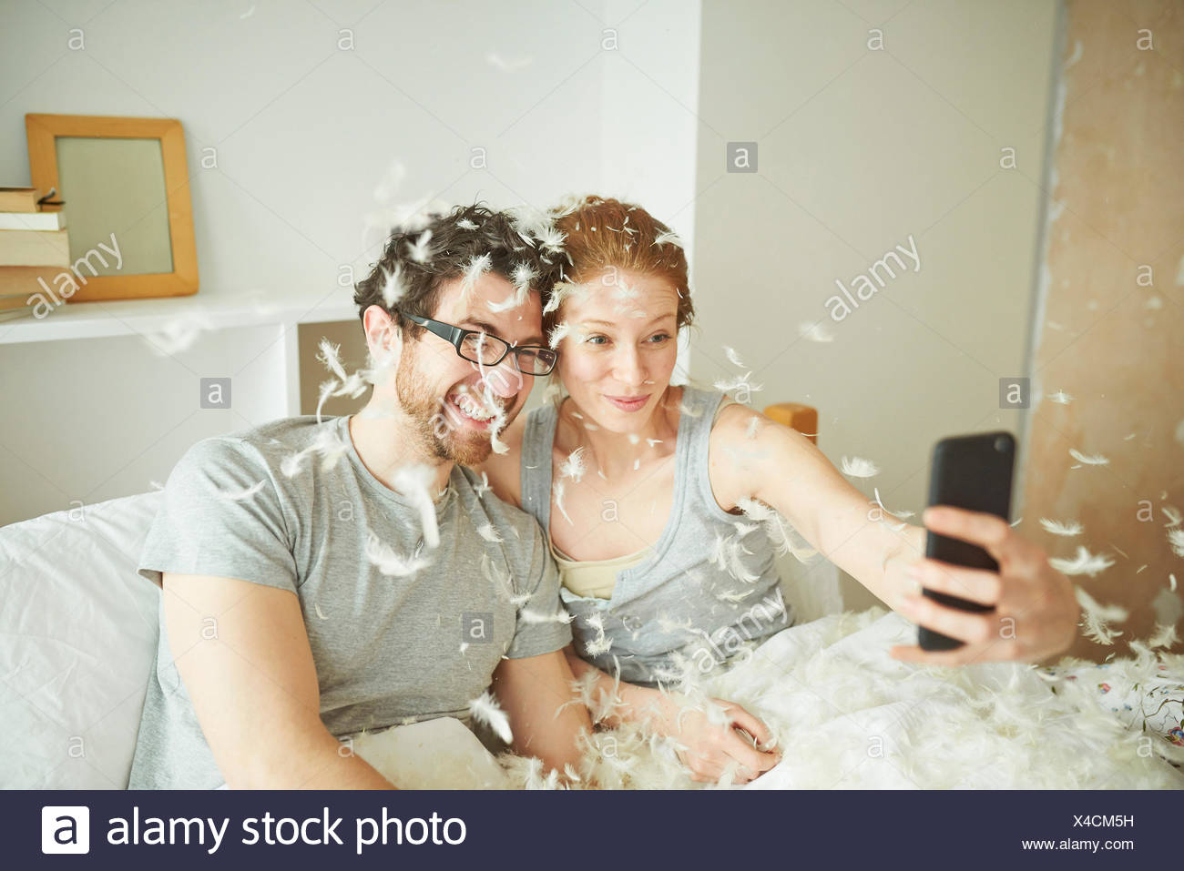 Mid Adult Couple Covered In Pillow Fight Feathers Taking