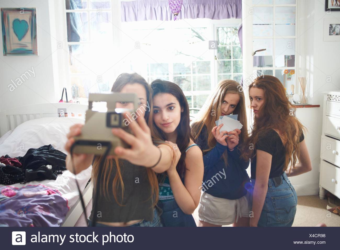 Four Teenage Girls In Bedroom Taking Instant Camera Selfie