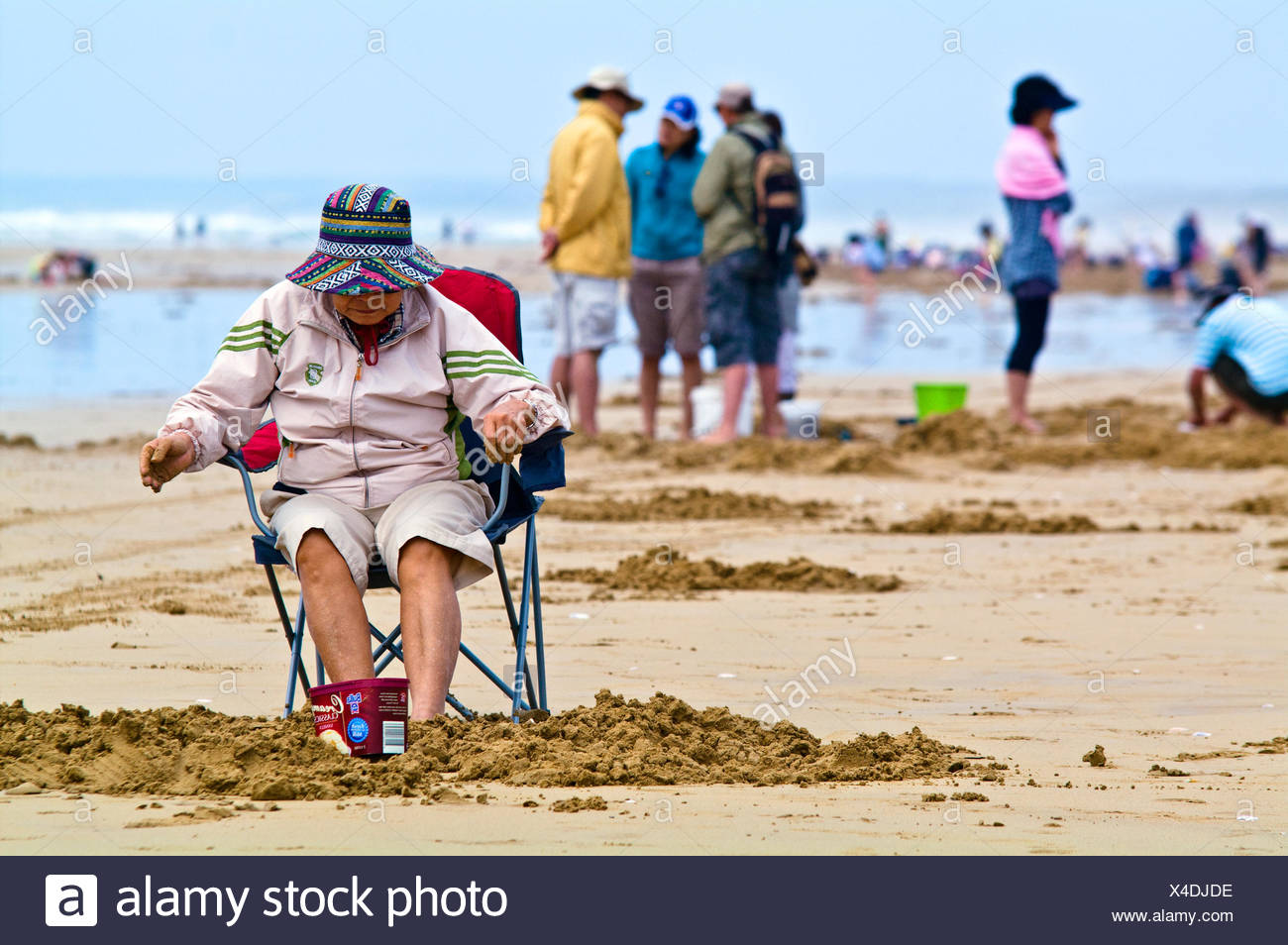An Elderly Woman Sleeps In A Beach Chair Surrounded By Pipi Fishermen Stock Photo Alamy