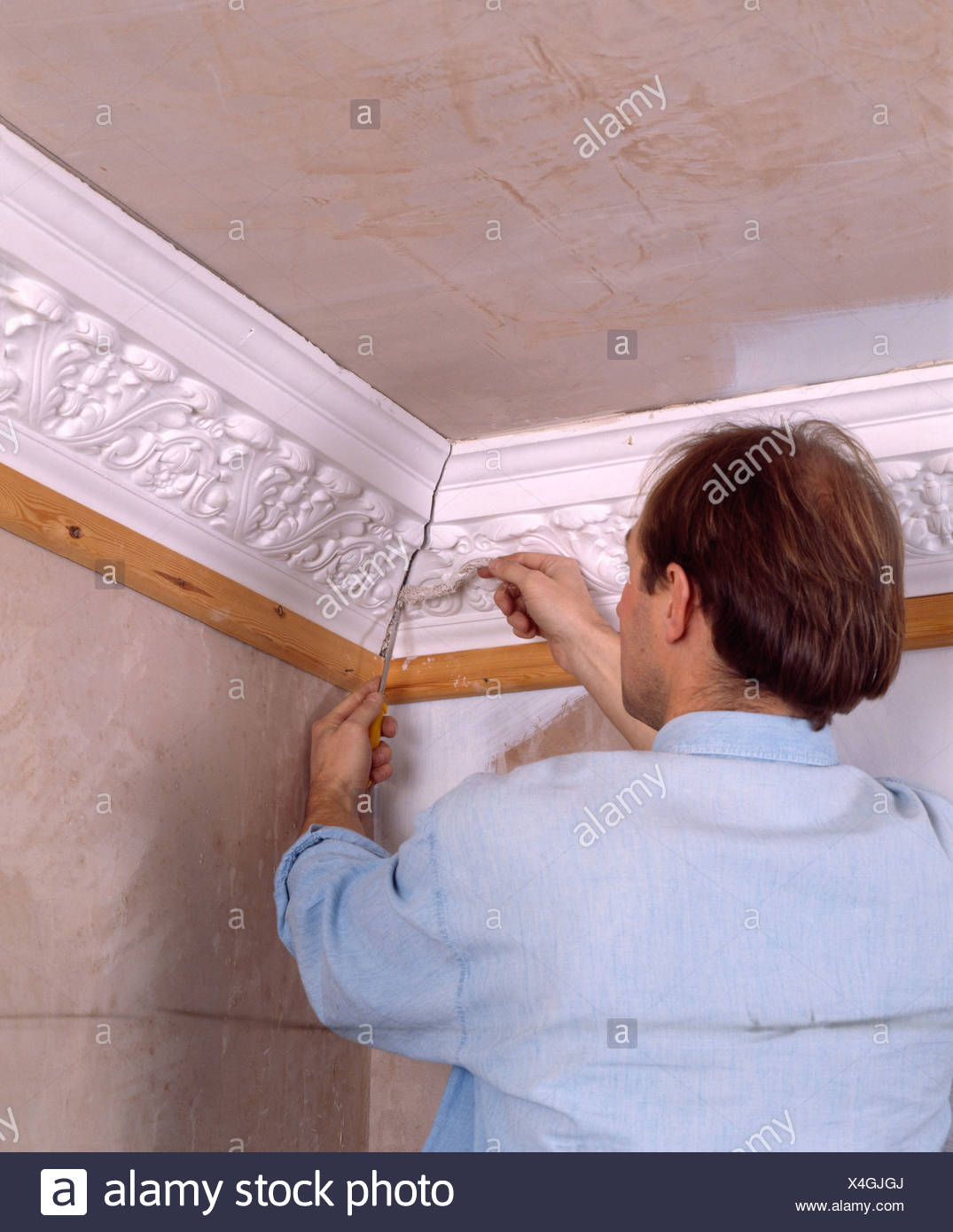 Close Up Of Man Repairing Plaster Ceiling Cornice Stock Photo