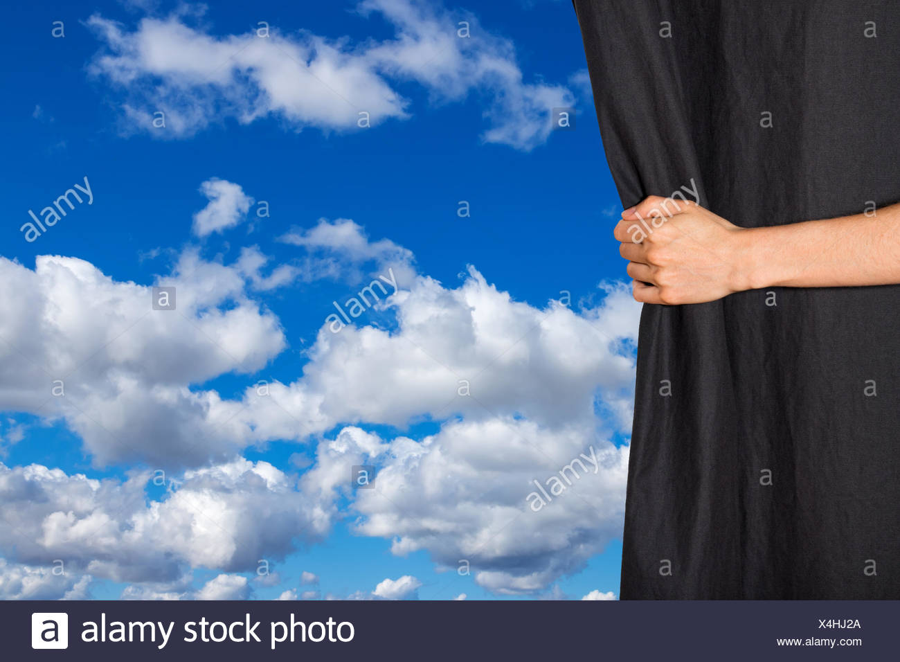 Hand Opening Black Curtain With Sky Behind It Stock Photo