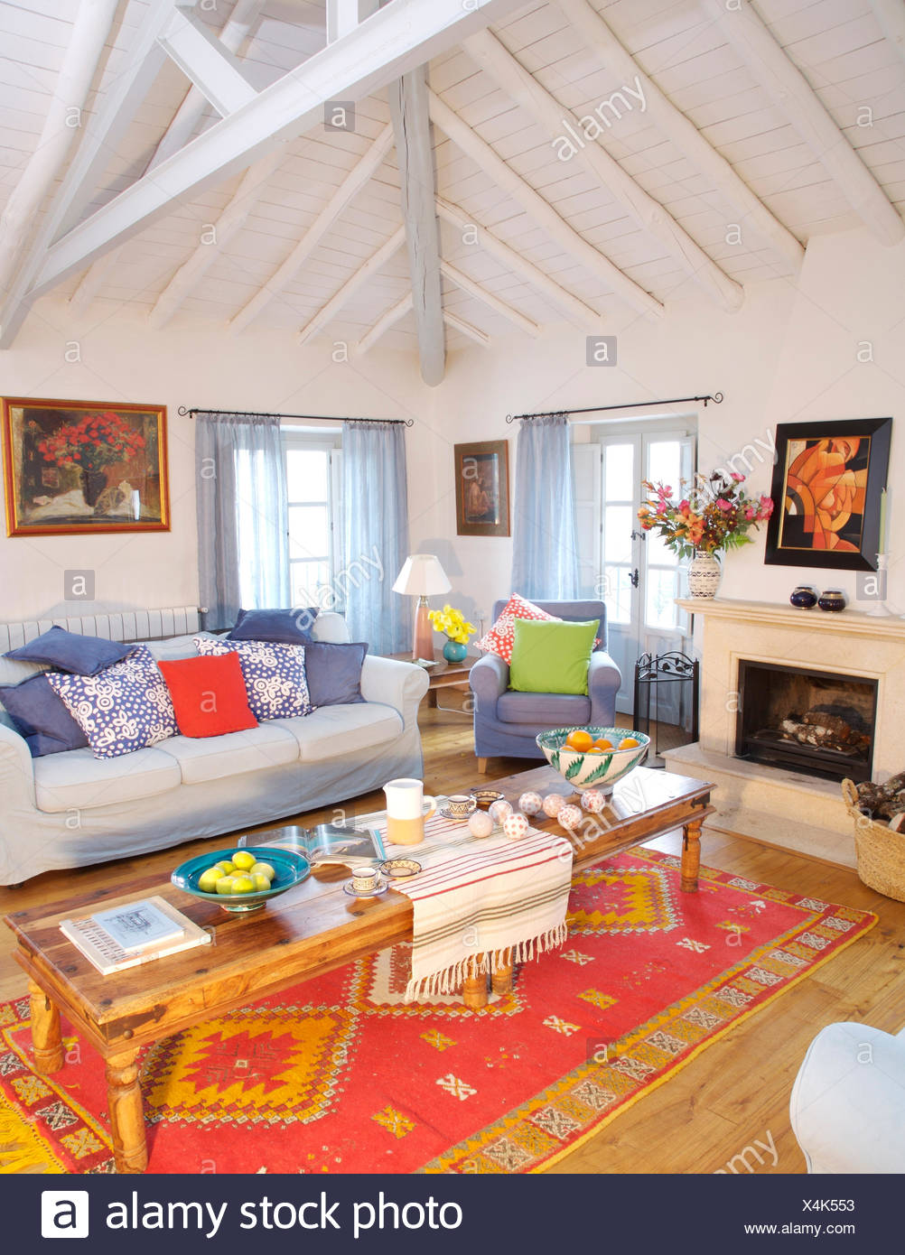 Rustic Wooden Coffee Table On Red Ethnic Rug In Spanish Country Living Room With White Painted Beamed Ceiling Stock Photo Alamy