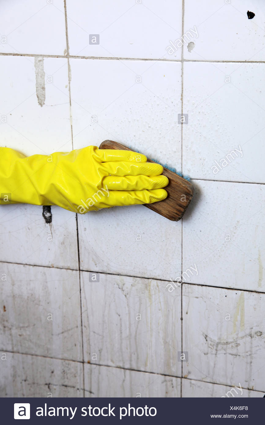 Gloved Hand Cleaning Dirty Old Tiles With Brush In A Bathroom