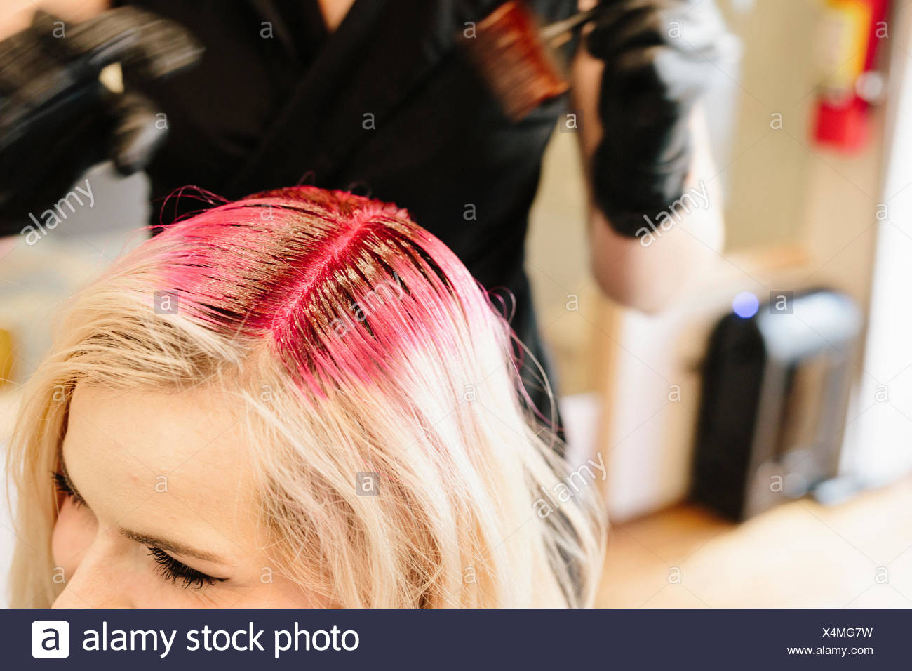 A Hair Colourist In Gloves Applying Red Hair Dye To A Client S