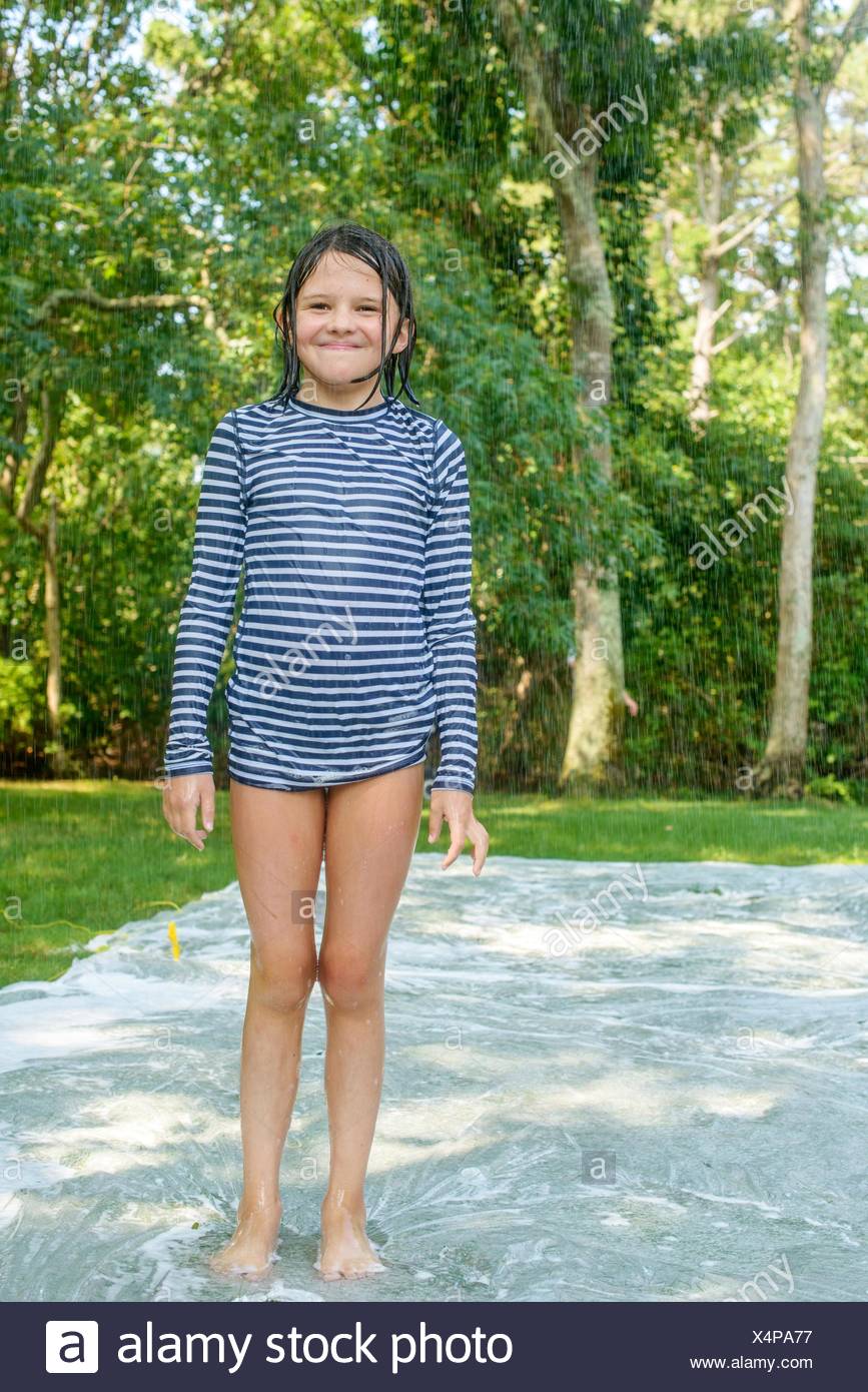 Portrait of young girl standing on slip n slide water mat in garden Stock  Photo - Alamy