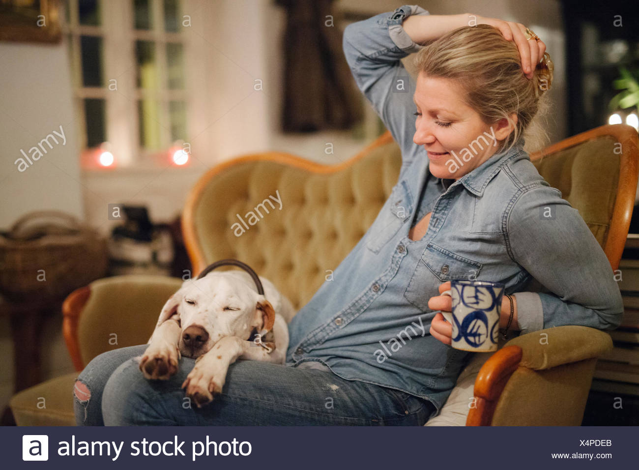 A Woman Seated On A Sofa With A Large Dog With His Head On Her Lap