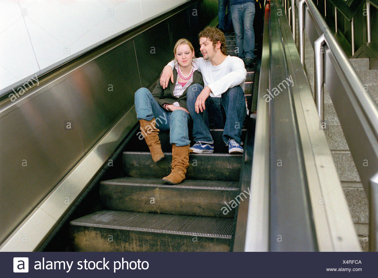 Couple sitting on escalator Stock Photo