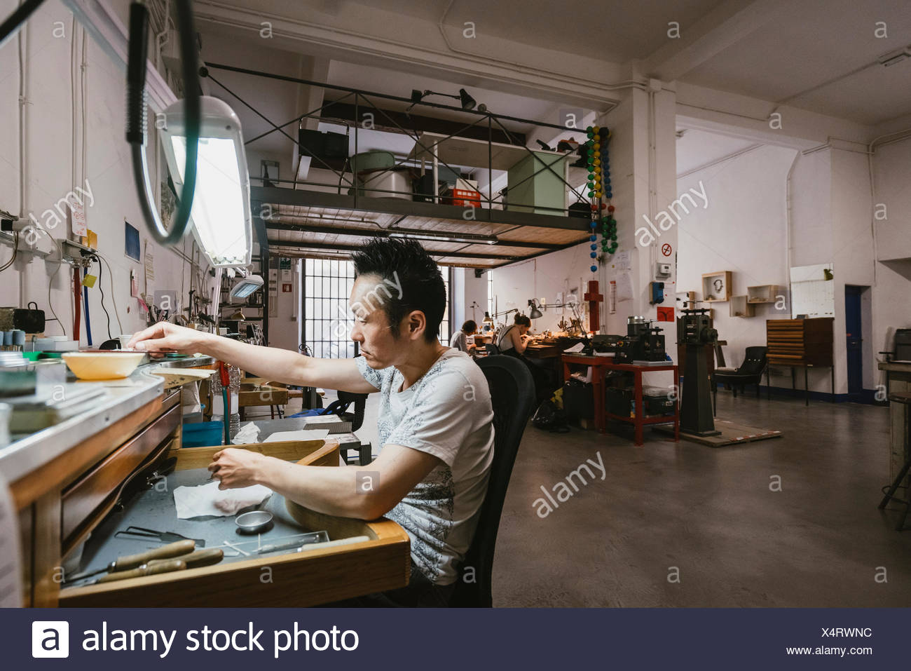 Male Jeweller Working At Jewellery Workshop Workbench Stock Photo