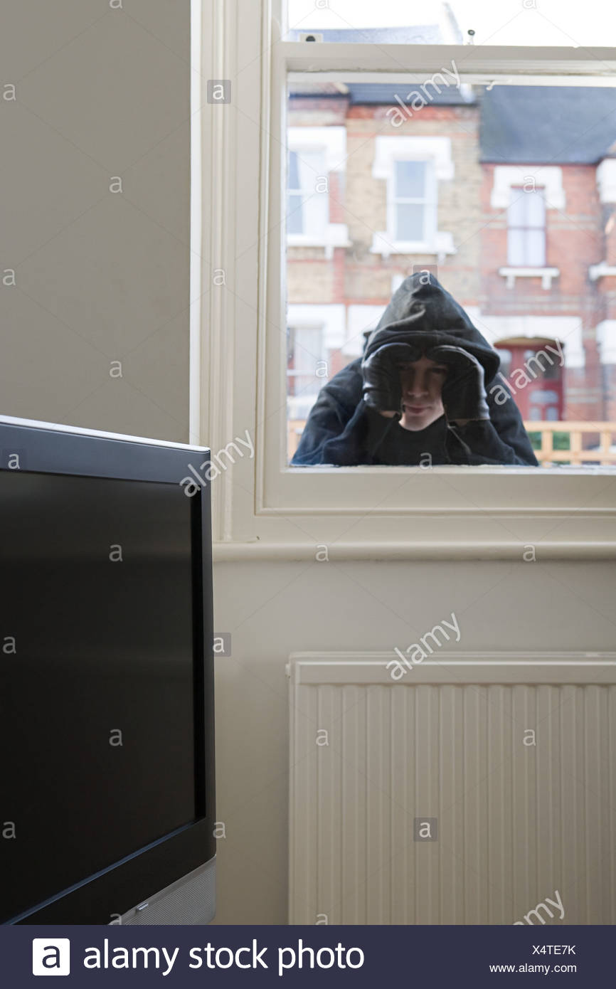 burglar-looking-through-window-X4TE7K.jp
