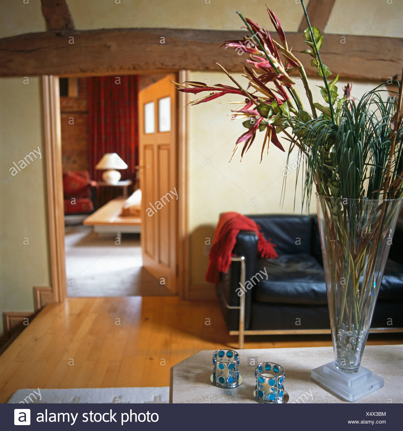 Flowers In Tall Glass Vase On Table With Beaded Candle Holders In