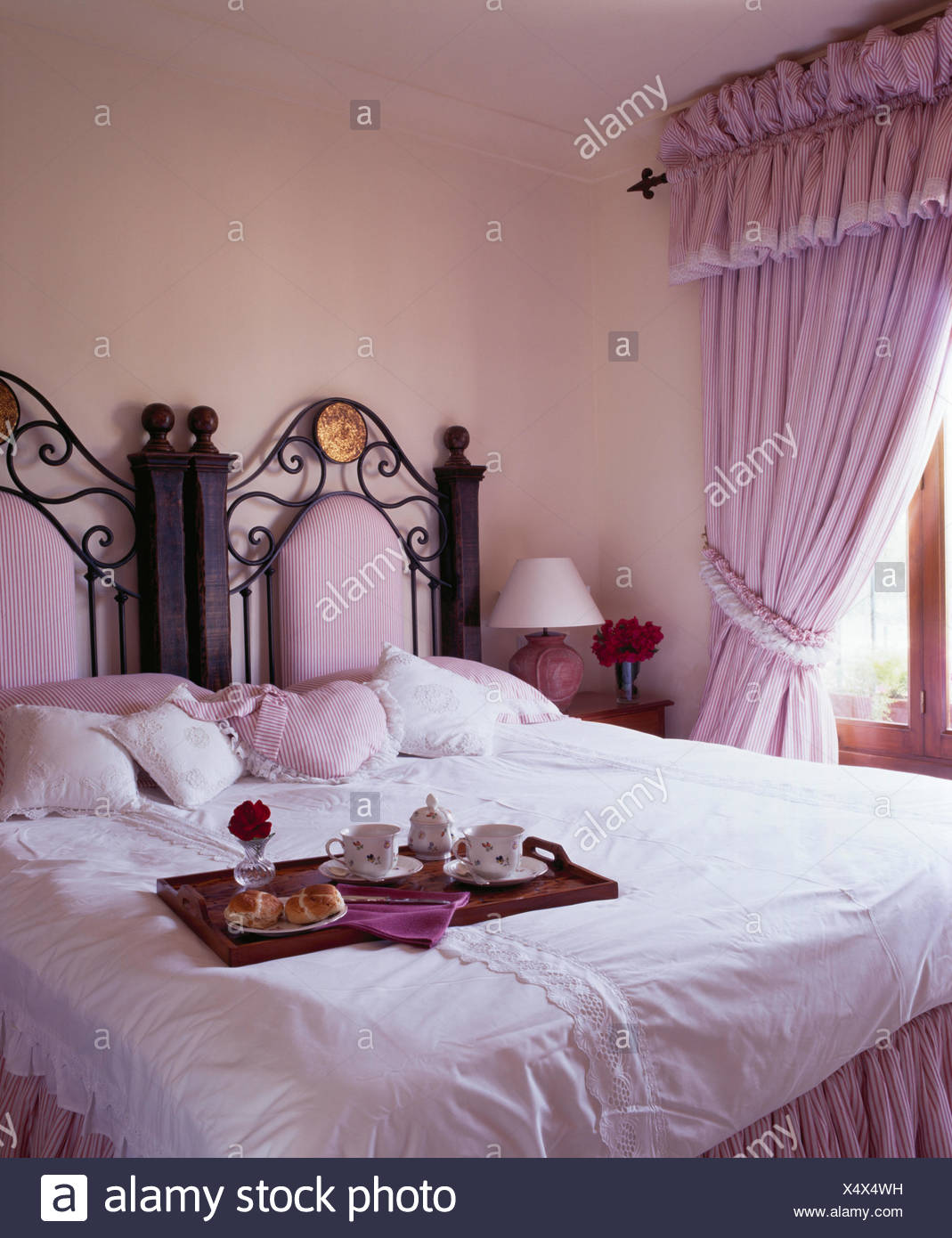 Breakfast tray on a wrought iron antique bed with white duvet in ...