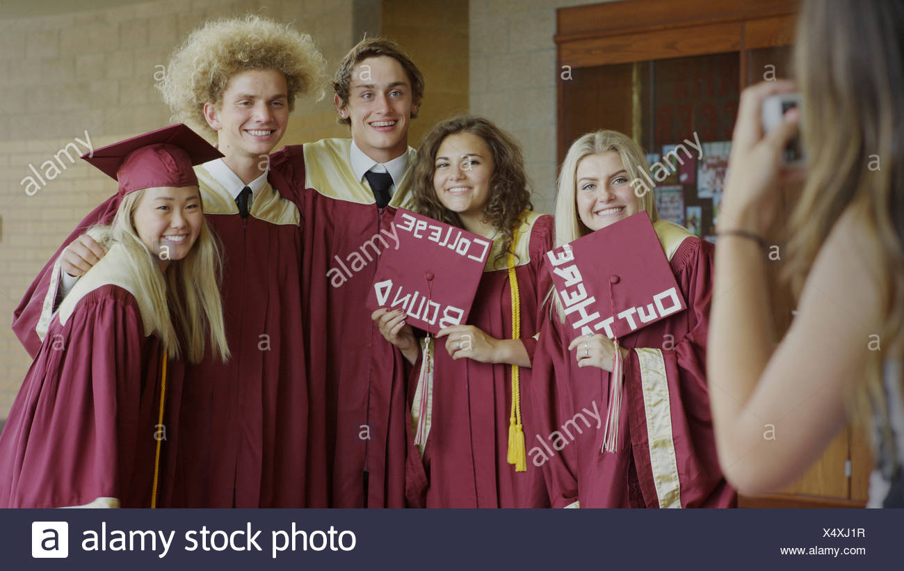 Smiling Students Posing With Decorated Mortarboards At Graduation