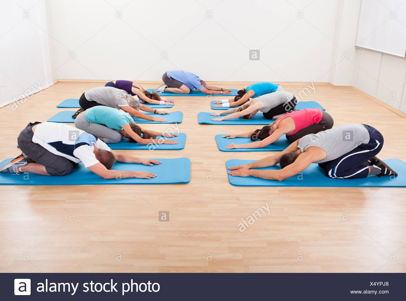 A Mixed Class Of Men And Women Stretching On Individual Floor Mats